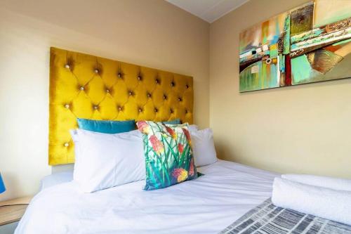 um quarto com uma cama branca e uma cabeceira amarela em #AlimamaSpaces: Bonito's Waterfall Ridge em Midrand
