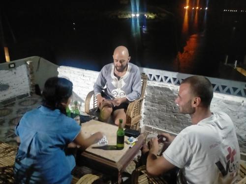 een groep mensen die rond een tafel zitten bij Seko Kato Nile View Hostel in Aswan