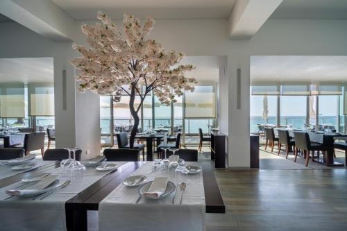 a dining room with tables and chairs and a tree at Arribas Sintra Hotel in Sintra