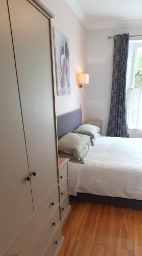 a bedroom with a bed and a dresser and a mirror at Midway Guest House in Torquay