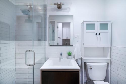 a white bathroom with a toilet and a sink at 1290-8 New Renovated 2 Bedrooms in UES in New York