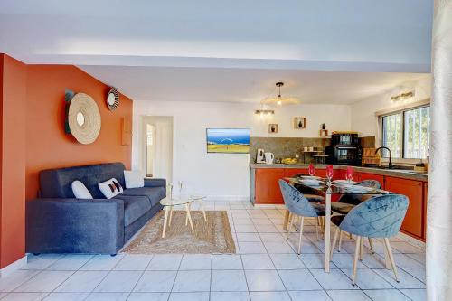 ein Wohnzimmer mit einem blauen Sofa und einer Küche in der Unterkunft Bec Rose - Clim - Wi-fi - Jardin in Saint-Leu