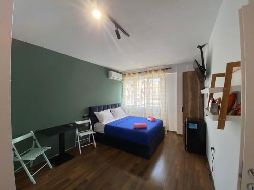 een slaapkamer met een blauw bed, een bureau en een stoel bij What's Up Tirana in Tirana