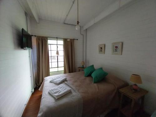 Un dormitorio con una cama con almohadas verdes y una ventana en Las Nativas de Areco en San Antonio de Areco