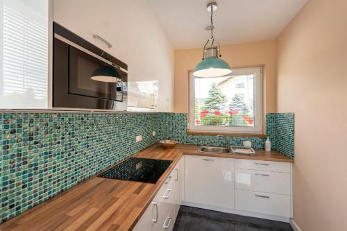 a kitchen with green tiles on the wall at Apartamenty Mozaika - centrum Zdroju in Lądek-Zdrój