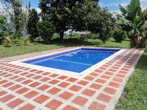 una piscina en un patio con suelo de ladrillo en FINCA LA COLONIA en Buga