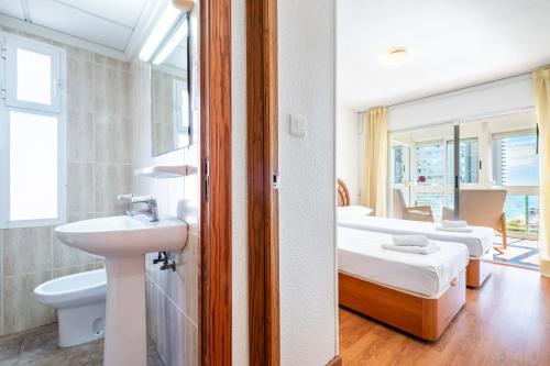 un bagno con lavandino e una camera con due letti di Niza 11-A Apartment Levante Beach a Benidorm