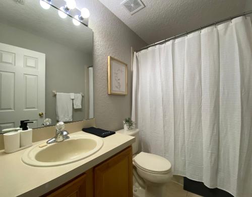 a bathroom with a sink and a toilet and a mirror at Beautiful 4 Bedroom Vacation Home at Regal Palms Resort, close to Disney World in Davenport
