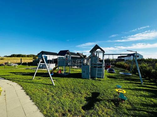 un parque con parque infantil con columpios en Domki Perełka en Mielenko