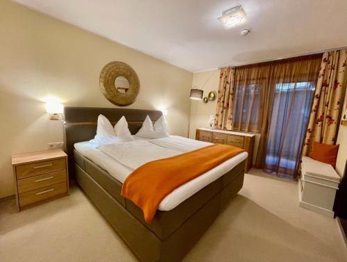 a bedroom with a large bed with an orange blanket at Hotel Alta Vista in Neukirchen am Großvenediger