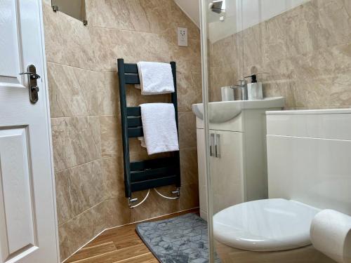 uma casa de banho com chuveiro, WC e toalhas em Comfort Home em Gillingham