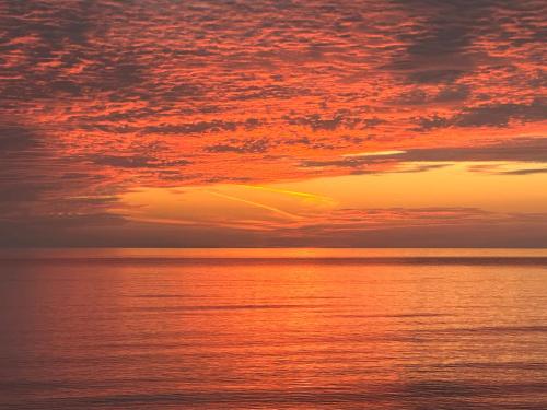un coucher de soleil sur l'océan avec un ciel nuageux dans l'établissement LIMANI, à Grigoleti