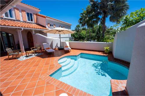 un patio trasero con piscina y una casa en Villa III en Lance aux Épines