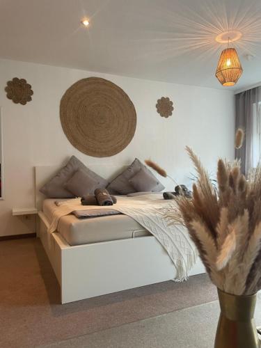 een slaapkamer met een wit bed en een mand aan de muur bij Kingsize Bett BOHO Apartment mit Tiefgarage nähe Salzburg in Freilassing