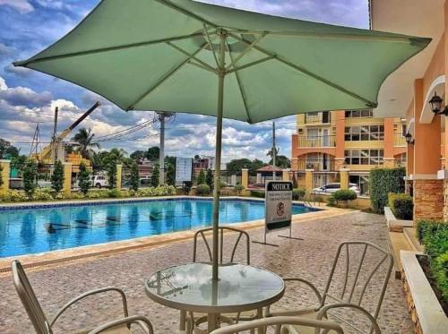 a table with a green umbrella next to a pool at Cozy 1BR Condo near Airport Davao City in Davao City