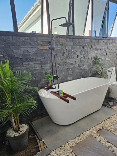 a bath tub sitting in a bathroom with plants at Muguet by Ibiscot development in Kampala