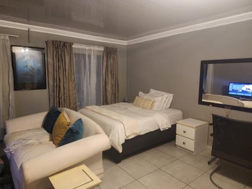 a bedroom with a bed and a couch and a television at Tenlet guesthouse in Pretoria