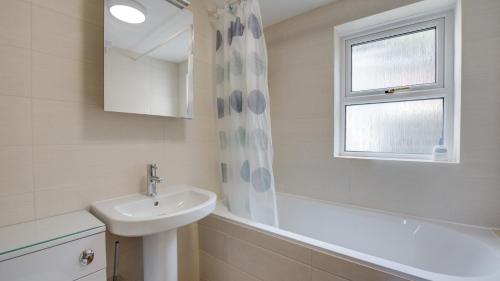 een witte badkamer met een wastafel en een raam bij Ael Y Don, Langland in Newton
