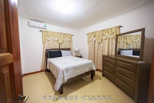 um quarto com uma cama, uma cómoda e um espelho em Shan's Manor.... Excellent Location!!! em Kingston