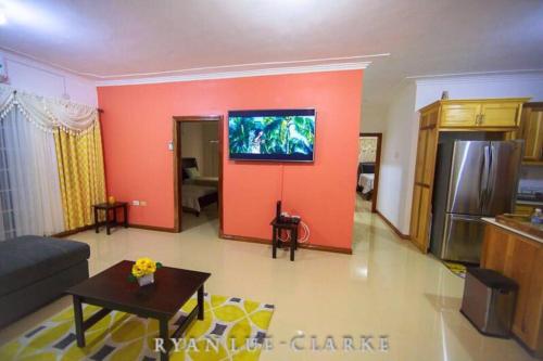 金斯敦的住宿－Shan's Manor.... Excellent Location!!!，客厅设有带平面电视的橙色墙壁。
