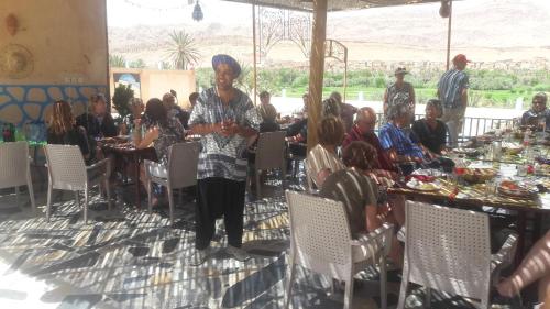 Una donna in piedi di fronte a un gruppo di persone sedute ai tavoli di MAISON D'HOTES IRIKI a Tinerhir
