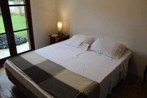 a bedroom with a large bed with a window at Casa da Uba Una in Ubatuba