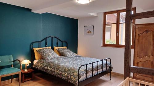 ein Schlafzimmer mit einem Bett und einer blauen Wand in der Unterkunft Les Myrtilles in Barr