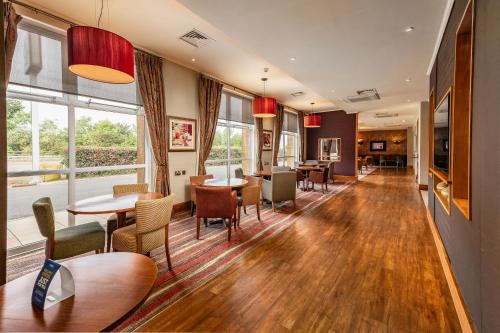 a restaurant with tables and chairs and windows at The Milestone Peterborough Hotel - Sure Collection by BW in Peterborough