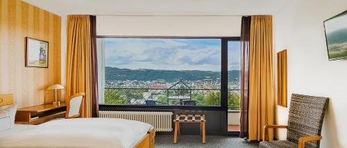ein Hotelzimmer mit einem Bett und einem großen Fenster in der Unterkunft Vintage Hotel Petrisberg in Trier