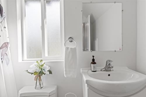 a white bathroom with a sink and a window at Private Mountainside Home in Chilliwack