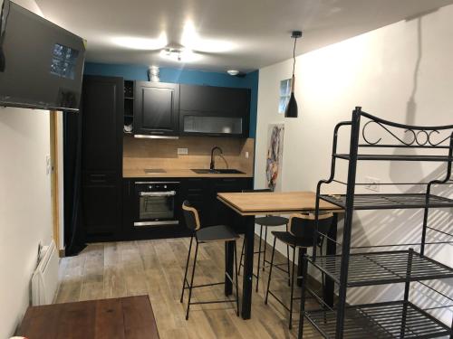 une cuisine avec des armoires noires, une table et des chaises dans l'établissement Fromental, à Saint-Côme-dʼOlt