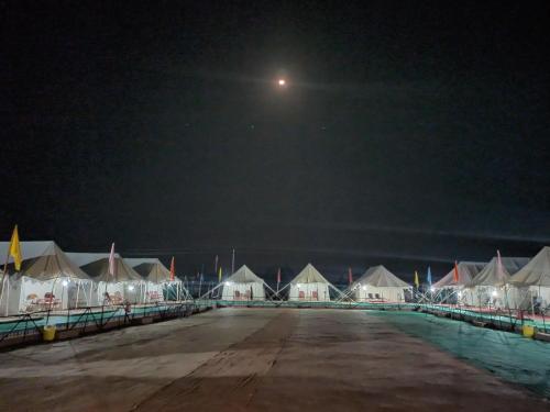 a row of tents at night with a full moon at Rann Kandhi in Dhordo