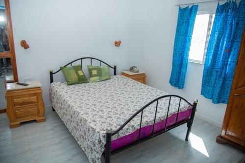 Schlafzimmer mit einem Bett und blauen Vorhängen in der Unterkunft Dar Amazigh in Tozeur