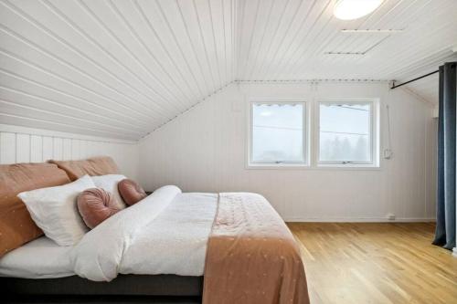 um quarto branco com uma cama e 2 janelas em Stort hus sentralt 4 roms em Lillestrom