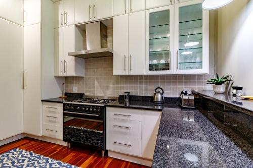 a kitchen with white cabinets and black counter tops at Christies at 32 on Russell in Nelspruit