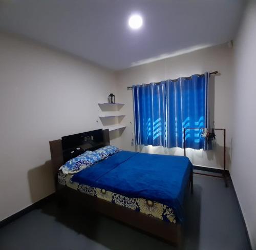 a bedroom with a blue bed and a window at Sa-Ra's vakantiehuis in Paramaribo