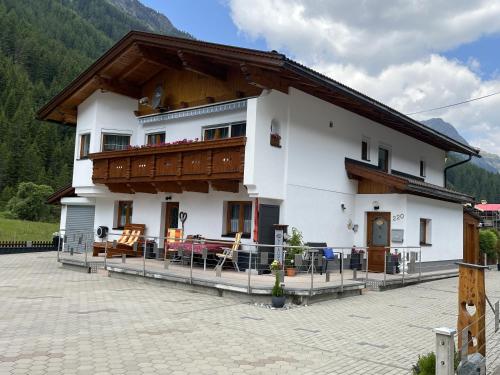 a large white building with a balcony with tables and chairs at Apartment Familie Thomas und Angelika Melmer in Sankt Leonhard im Pitztal