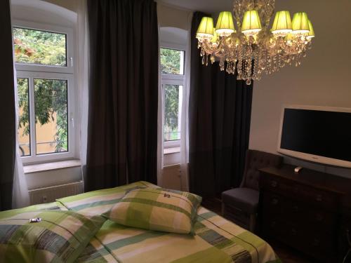 a bedroom with a bed and a chandelier and windows at Elbsandstein Apartments Altstadt in Erfurt