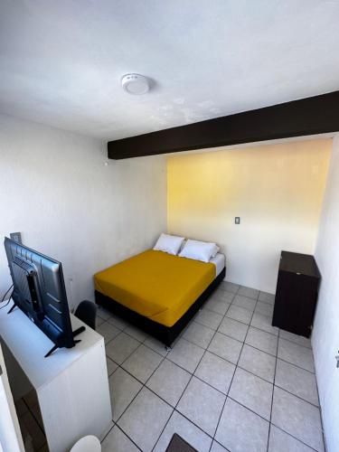 a small room with a bed and a tv at CASA MARIN MANDIMBO in Oaxaca City