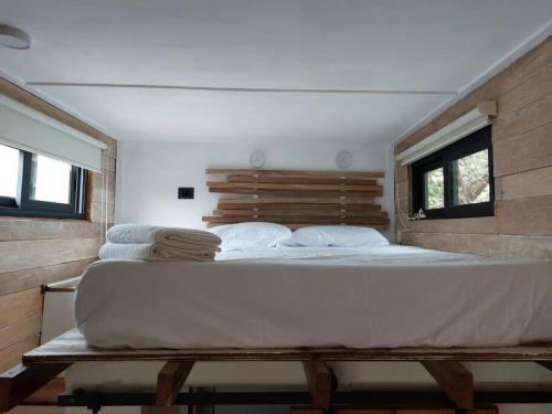 a large white bed in a room with two windows at Polita Tiny House, con piscina, a 200m de la playa in Holbox Island