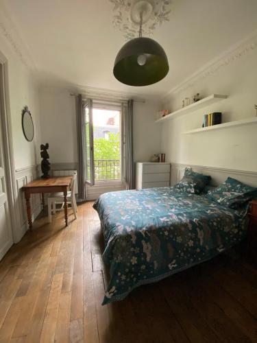 Schlafzimmer mit einem Bett, einem Tisch und einem Fenster in der Unterkunft Appartement à 50m de Paris in Clichy