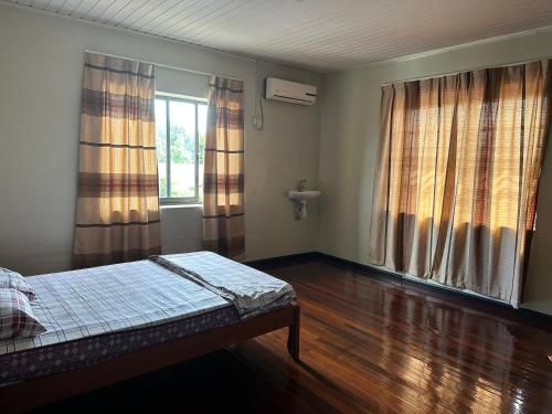 een lege kamer met een bed en twee ramen bij Tweederijweg Apartments in Paramaribo