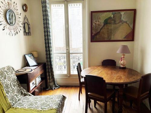 un salon avec une table et des chaises et une fenêtre dans l'établissement Flat in Montmartre/Abbesses, à Paris