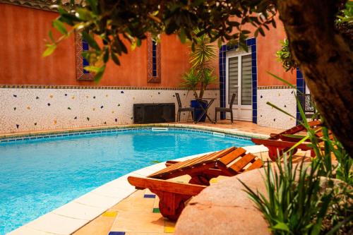 a swimming pool with a bench next to a building at Logis Hôtel Restaurant de la Paix in Lodève