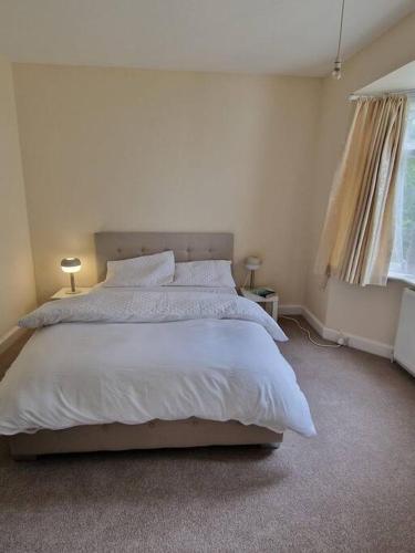 a bedroom with a large bed with white sheets and pillows at Lovely 2 bedroom bungalow ! in Saint Albans