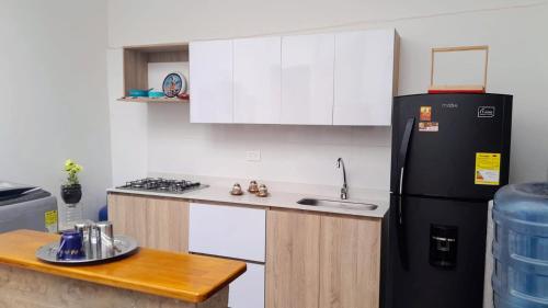 eine Küche mit einem schwarzen Kühlschrank und einer Spüle in der Unterkunft Casa de huéspedes la Casona. in Medellín