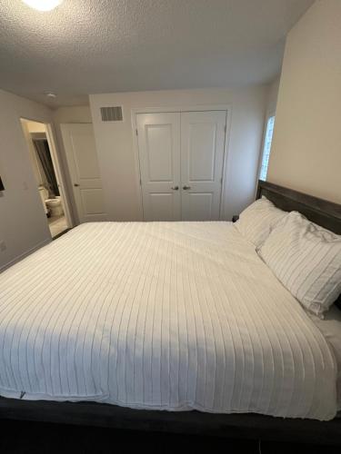 a bedroom with a large bed with white sheets at ON Residence in Hamilton