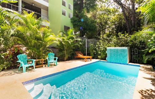 una piscina con 2 sillas y una mesa junto a un edificio en Penthouse Suite w/ Ocean and Pool View, en Nicoya