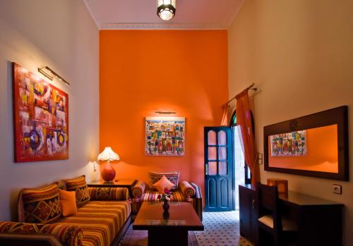 a living room with orange walls and a couch at Riad Maison Du Sud in Essaouira