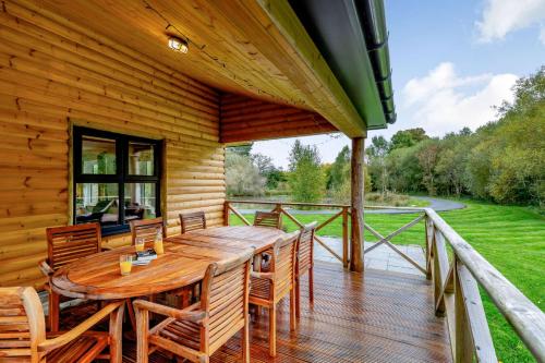 雷雅特的住宿－Rhosllyn Retreats - Lakeside Lodge，木制甲板配有木桌和椅子